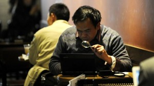 chinois se servant d'une loupe pour lire sur son écran d'ordinateur