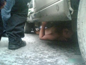 un chinois nu caché sous une voiture