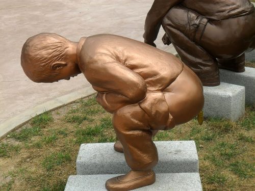 sculpture d'enfant qui fait caca